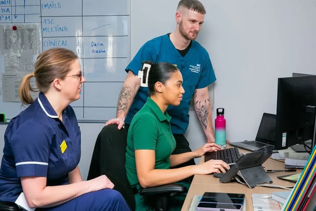 Three NHS clinicians collaborating around a workstation in a community office