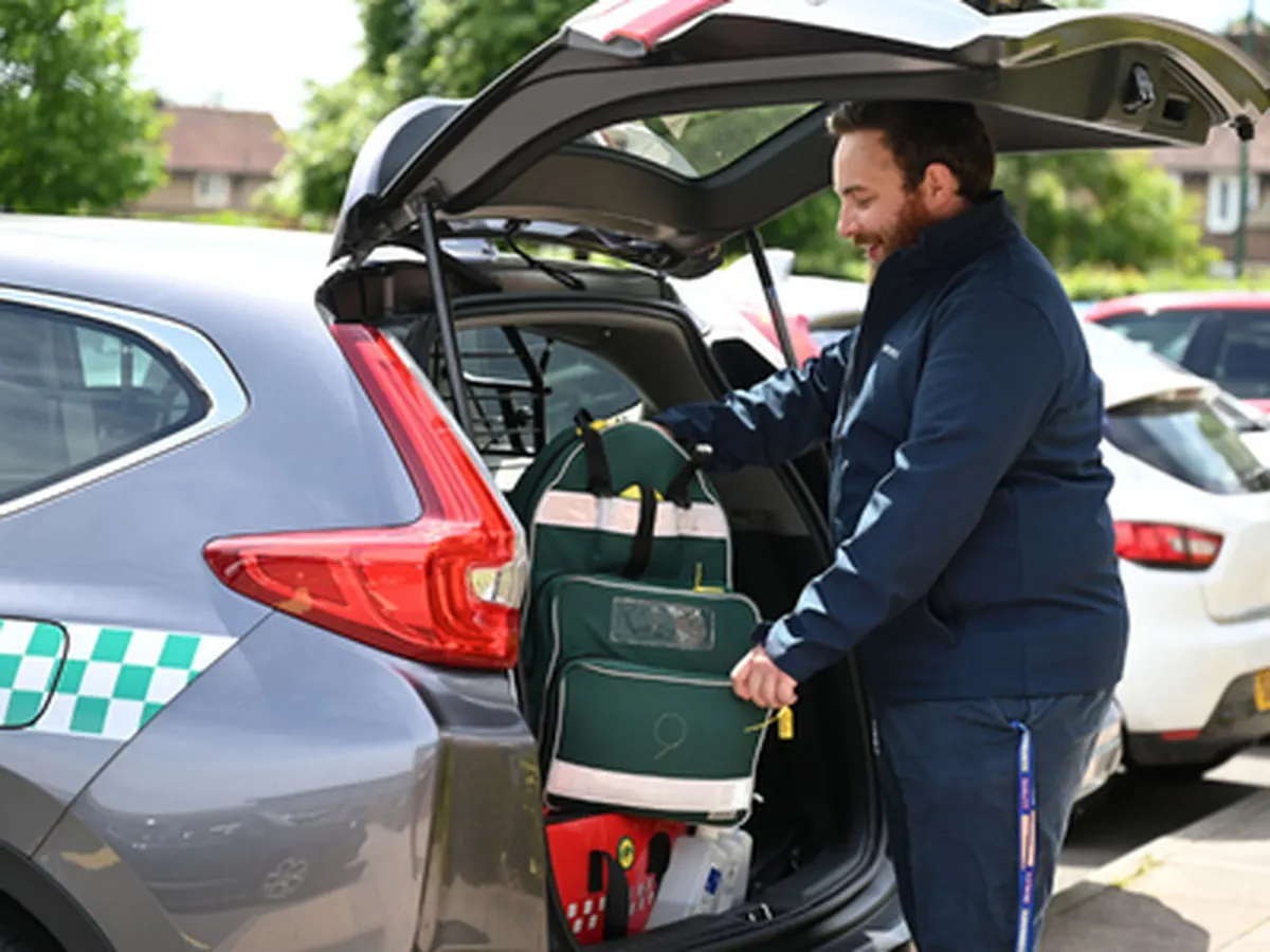 A paramedic loading an emergency response bag into a community response car